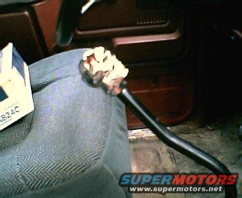 Close-up of a car's interior showing a part with a white box labeled '824C' and a black cable with a connector